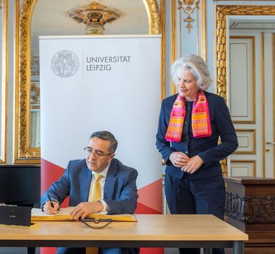 The Ambassador of India to Germany, Ajit Vinayak Gupte, signed Leipzig University’s Golden Book. Standing beside him is Rector Professor Eva Inés Obergfell. Photo: Swen Reichhold Zu sehen ist sitzend und ins Goldene Buch der Uni Leipzig schreibend der Botschafter Indiens in Deutschland, Ajit Vinayak Gupte. Neben ihm steht Rektorin Prof. Dr. Eva Inés Obergfell. Foto: Swen Reichhold